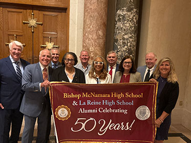 Bishop McNamara High School alumni holding up a sign celebrating 50 years Bishop McNamara High School alumni holding up a sign celebrating 50 years