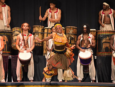 A student performs an African dance during a performance A student performs an African dance during a performance